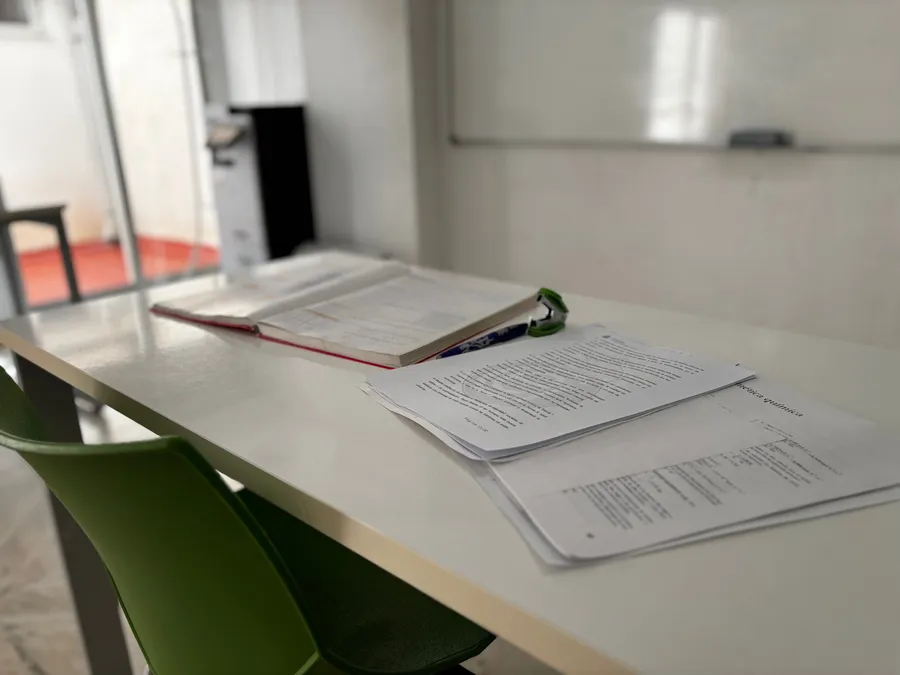 Mesa del aula con un libro abierto y apuntes